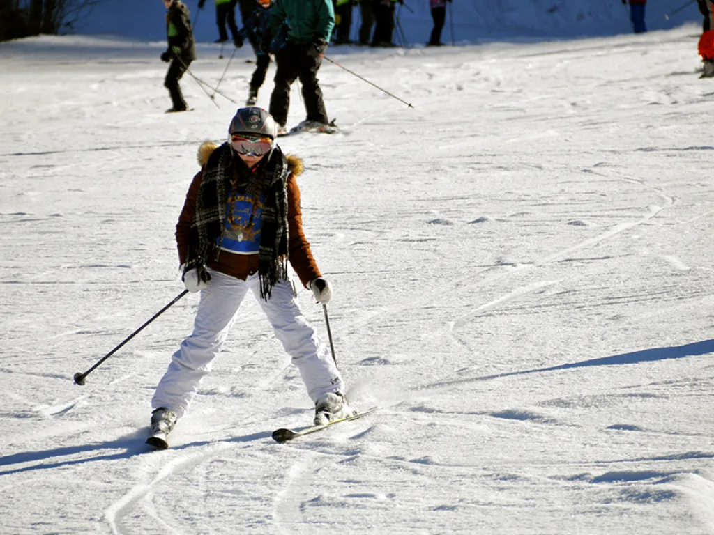 Skifahrerin in weißer Hose auf der Piste.